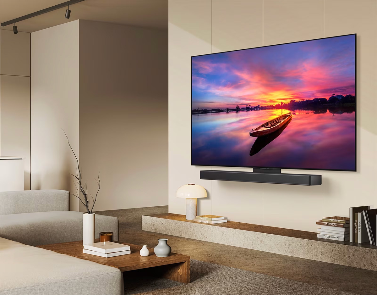 Μια LG OLED TV, OLED C4 στραμμένη 45 μοίρες στα αριστερά, απεικονίζοντας ένα όμορφο ηλιοβασίλεμα με μια βάρκα σε μια λίμνη, καθώς η τηλεόραση συνδέεται σε ένα LG Soundbar με τον βραχίονα Synergy σε ένα μινιμαλιστικό σαλόνι.